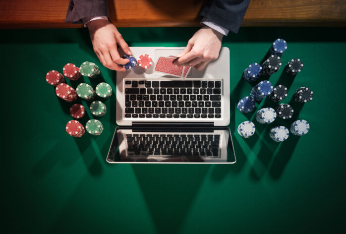 Man sitting with a laptop with poker chips on the table. Depiction of an online casino.