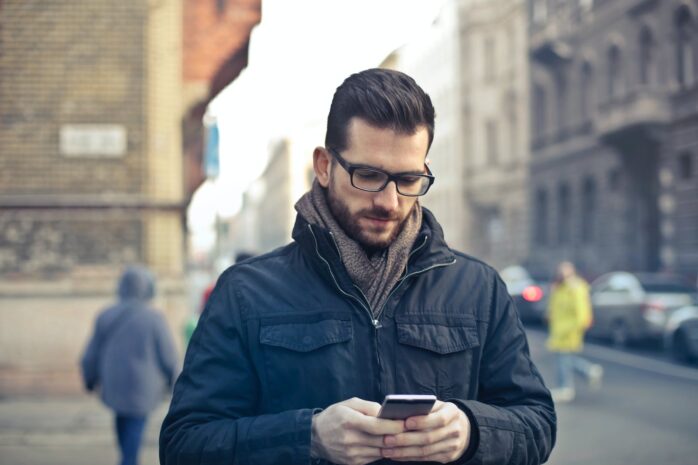 Man in a black jacket holding a phone. Depiction of a Mobile App.