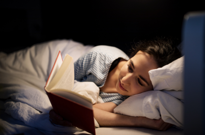 Woman reading a book before bedtime. Depiction of pre-bedtime routine in case of insomnia